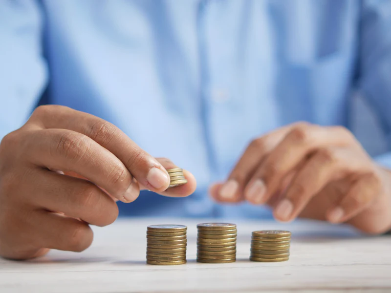 Hand stacking coins in rising piles